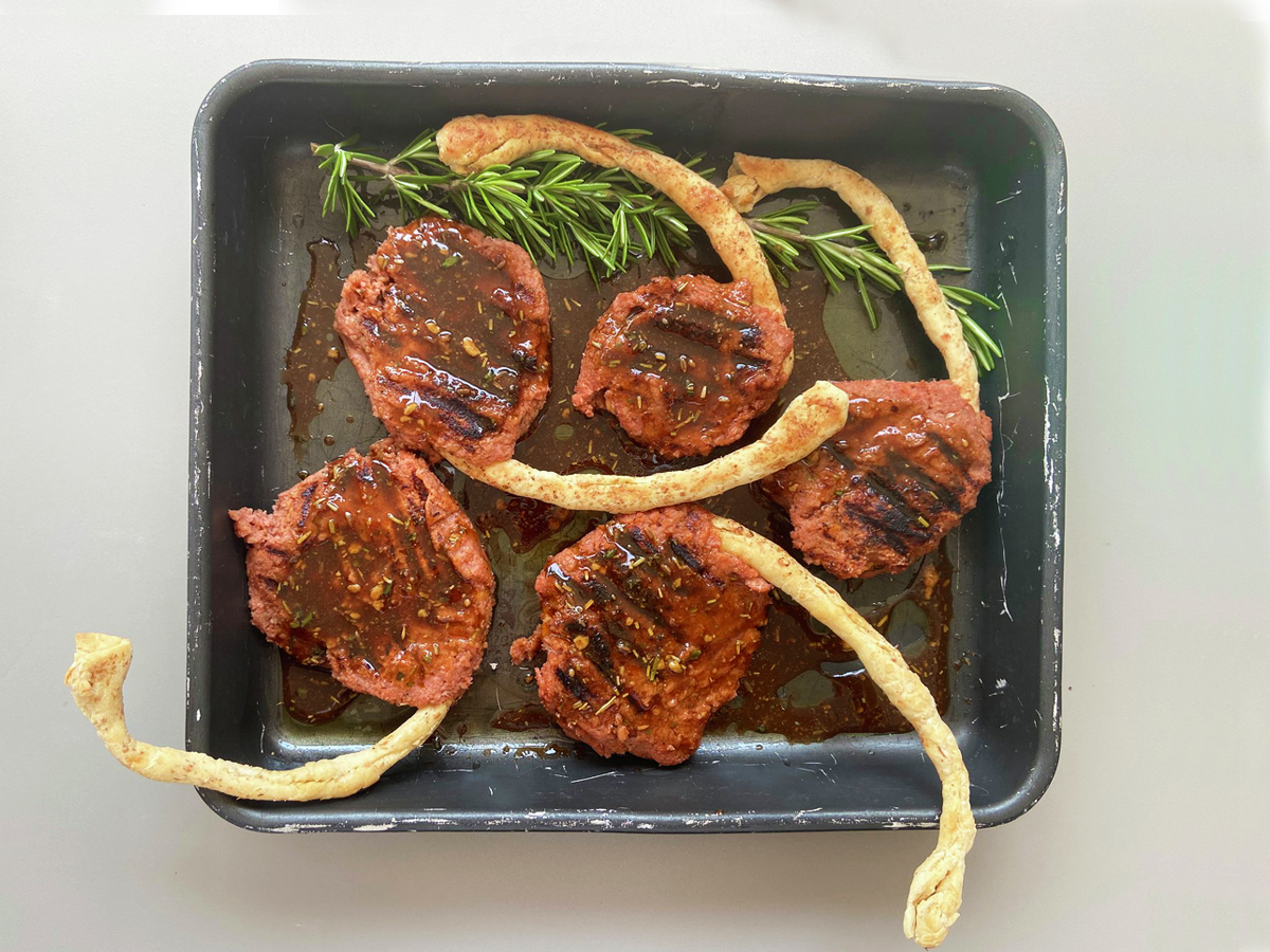 Sei costolette vegane nella teglia, con la salsa BBQ, prima di essere infornate