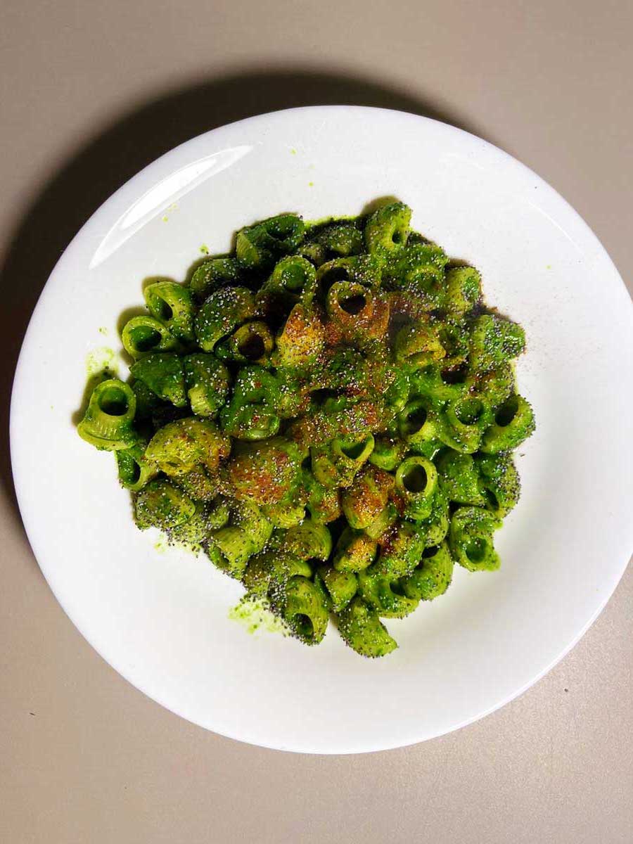 Primo piano dall'alto di un piatto di pasta con spinacini, semi di papavero e paprika