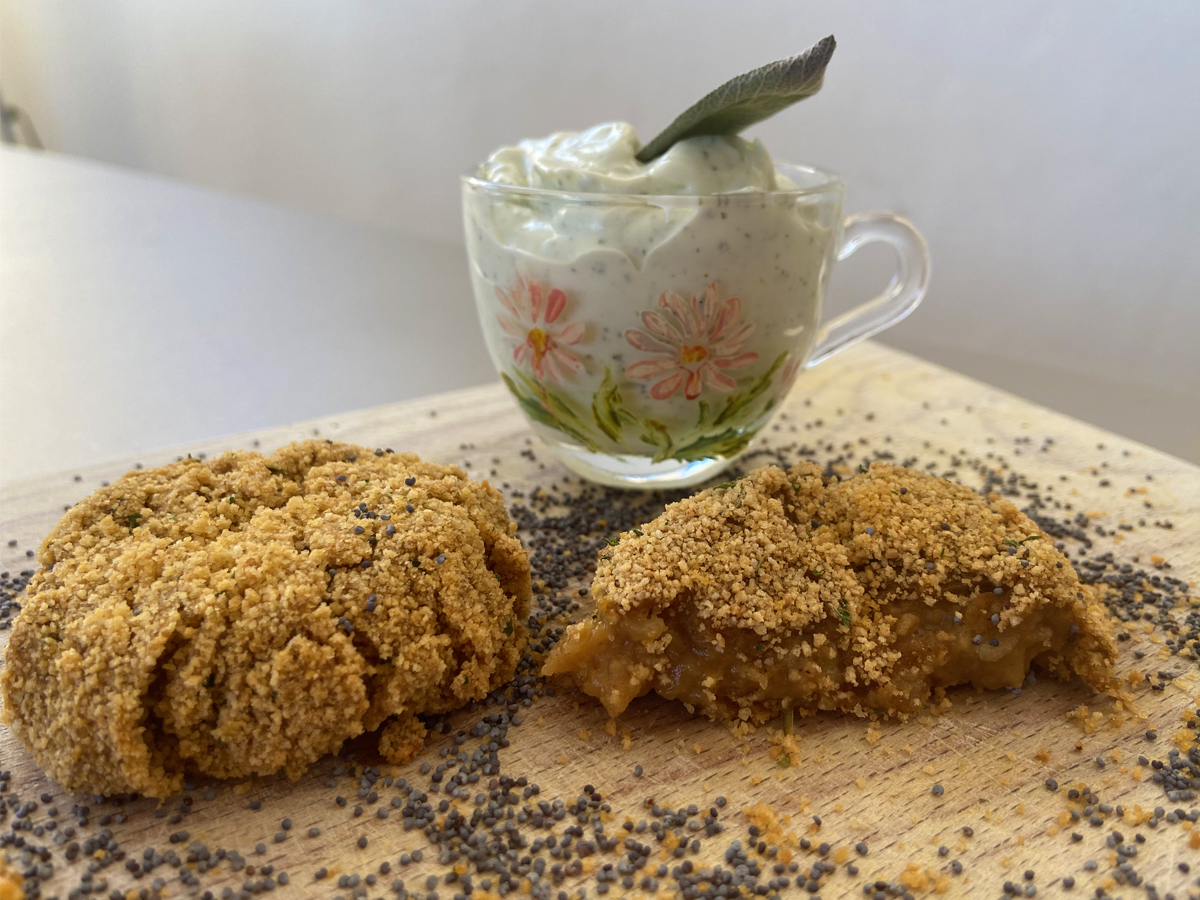 Primo piano di una polpetta e mezzo, con accanto la maionese vegana alla salvia