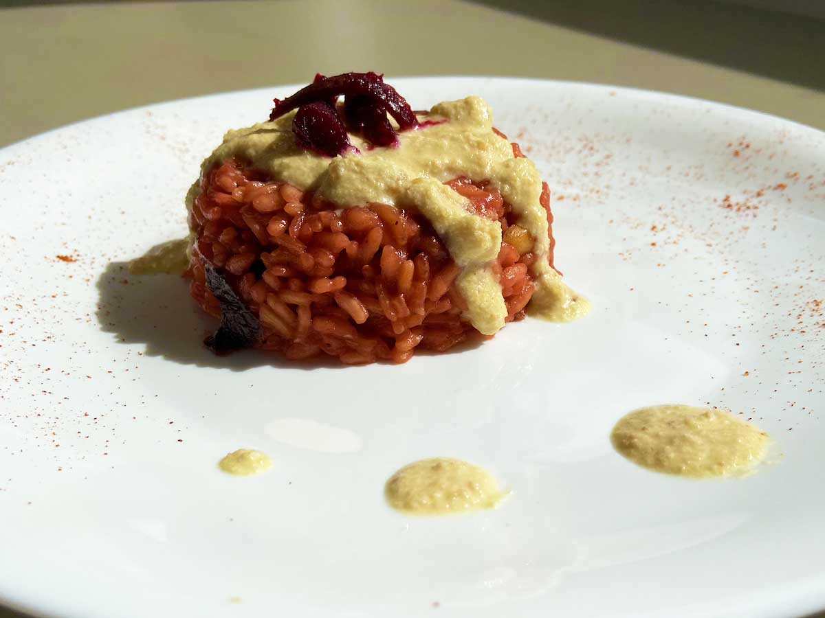 Primo piano di un piatto di risotto alla barbabietola e crema d'arachidi