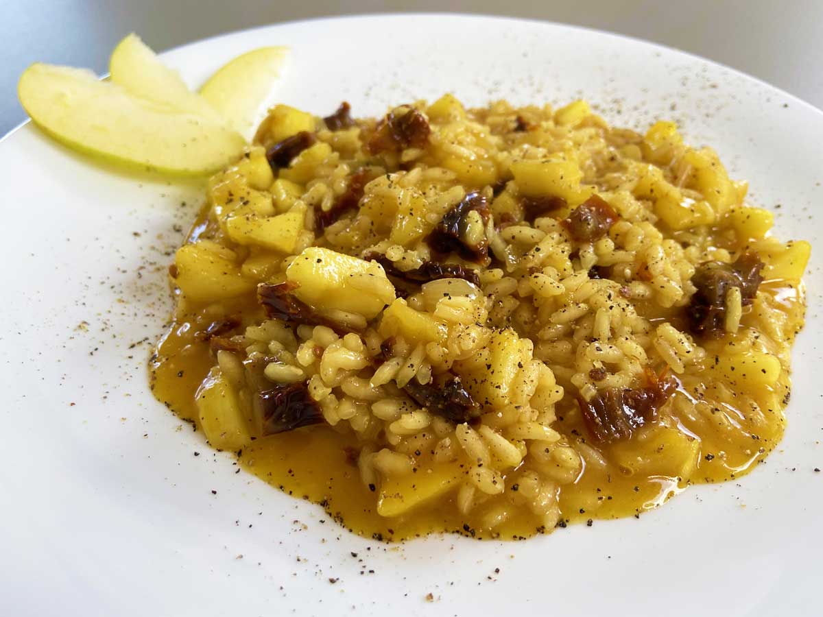 Primo piano di un piatto di risotto mele, zafferano e pomodori secchi