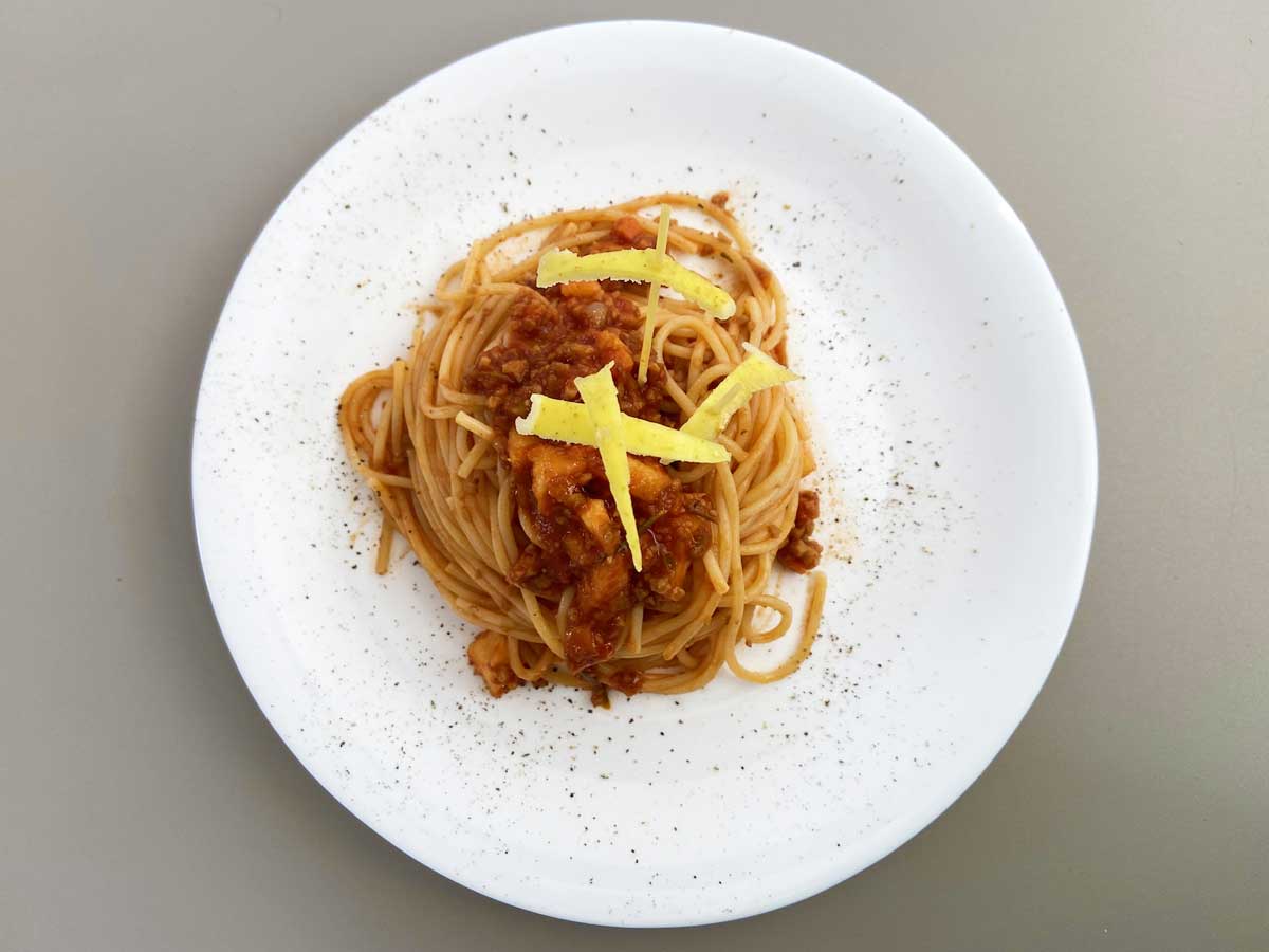 Piatto di spaghetti con ragù di mele e tofu croccante visto dall'alto