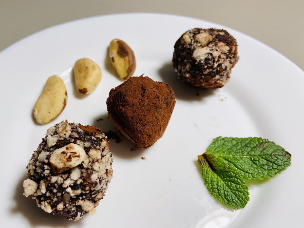 Primo piano di tre tartufi al cacao, con noci brasiliane per decorazione
