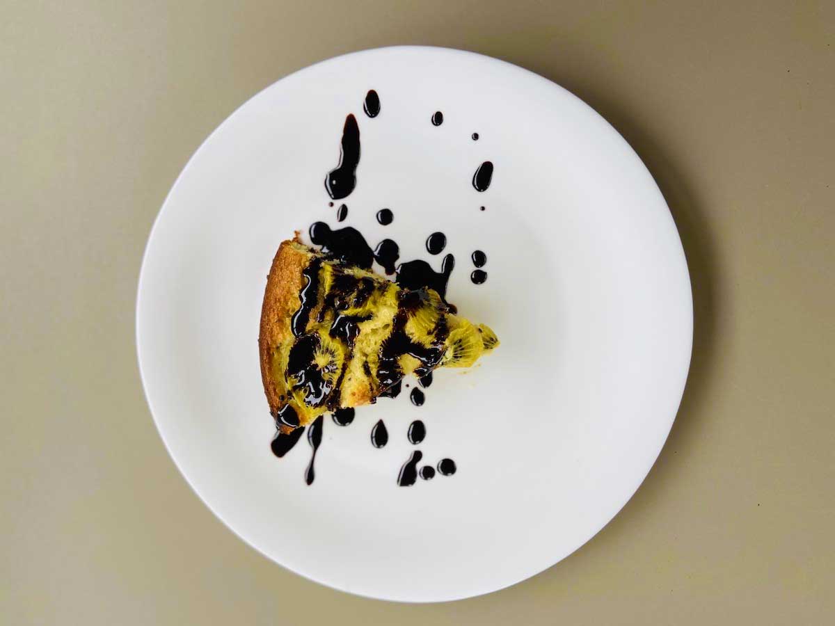 Fetta di torta di kiwi su un piatto con gocce di glassa al cioccolato
